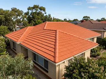 Restored and re-coated terracotta tile roof on a brick house