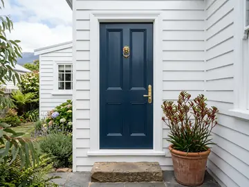 Deep navy front door with brass hardware on a white weatherboard house