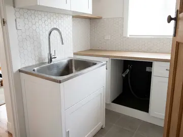 Renovated laundry with a stainless tub, gooseneck mixer and hexagon tile splashback